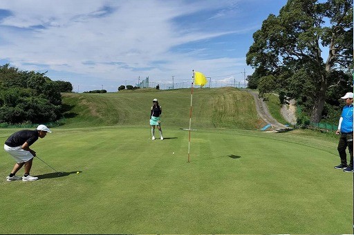 泉北ゴルフセンターのグリーンでラウンドレッスンを受ける生徒